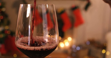 Red wine pouring into glass on wooden table during christmas time 4k