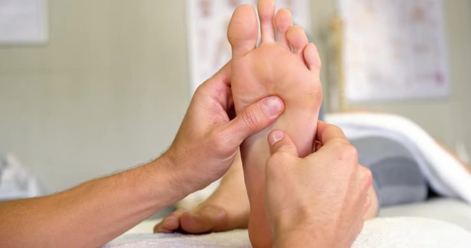 Physiotherapist giving foot massage to a woman in clinic 4k