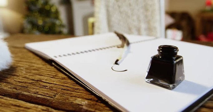 Close-up of diary with ink bottle and quill on table during christmas time at home 4k