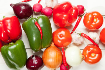 Fototapeta na wymiar Vegetables. Peppers, tomatoes, garlic, onions, eggplant, cucumber and radishes on a white wooden background