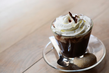 Close-up of a cup of hot chocolate with whipped cream and cocoa powder on wooden table