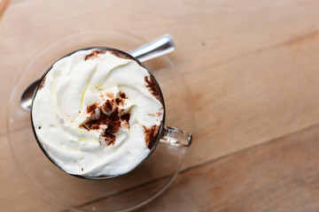 Close-up of a cup of hot chocolate with whipped cream and cocoa powder on wooden table