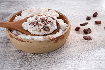 Cottage cheese with raisins in the dish on the wooden table in the kitchen. Tasty, sweet meal. Healthy eating and lifestyle.