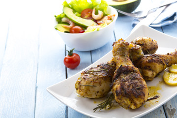 Grilled chicken legs fried tomatoes vegetables fresh salad avocado spices food in the kitchen
