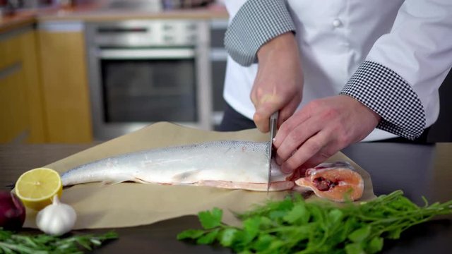 chef cutting salmon fish for cooking in kitchen