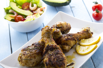 Grilled chicken legs fried tomatoes vegetables fresh salad avocado spices food in the kitchen
