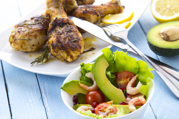 Grilled chicken legs fried tomatoes vegetables fresh salad avocado spices food in the kitchen
