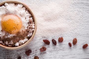 Recipe ingredients for cake. Cottage cheese, egg, semolina, raisins and cinnamon on the wooden table in the kitchen. Tasty, sweet meal. Healthy eating and lifestyle.