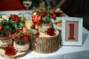 Obraz na płótnie Canvas Wedding rustic red flower decoration in a glass jar on a wooden stump