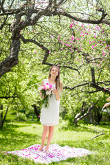 Fototapeta na wymiar Gentle happy brunette woman with bouquet of peonies in among the trees a sunny day