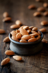 Almonds in a black bowl against dark rustic wooden background