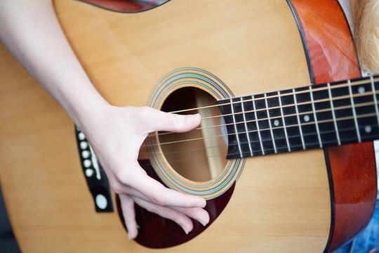 The woman plays an acoustic guitar
