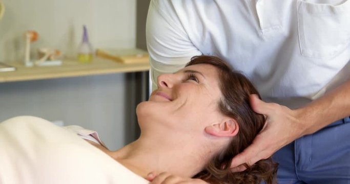 Physiotherapist giving head massage to a female patient in clinic 4k