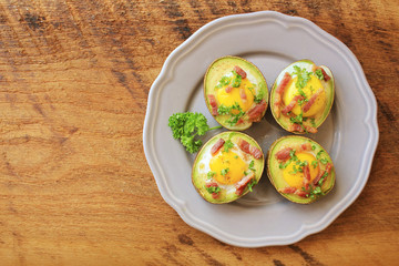 Avocado Egg Boats with bacon on wooden table. Top view.