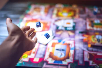 Hand throws the dice on the background of Board games © Artem