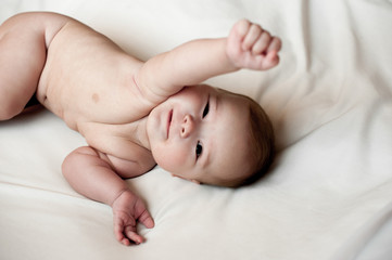 Soft picture of a beautiful baby boy laying on white bedding