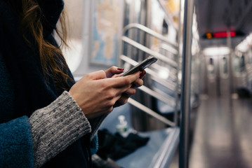 Women hands holding mobile phone in subway train