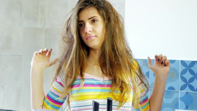 Woman with terrible messy hair looking in the mirror in the morning/Woman looking messy hair in mirror