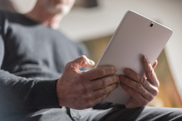 Senior man using his tablet, hard light effect
