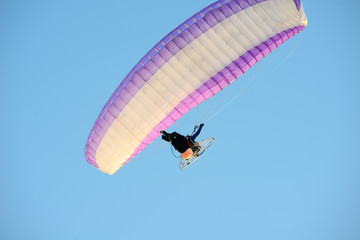 adventure man active extreme sport pilot flying in sky with paramotor engine glider parachute
