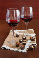 Two glasses of wine on a wooden table.  Candies.