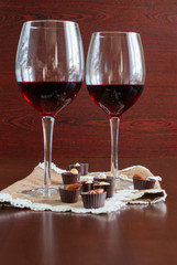 Two glasses of wine on a wooden table.  Candies.
