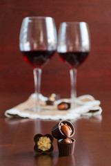 Two glasses of wine on a wooden table.  Candies.