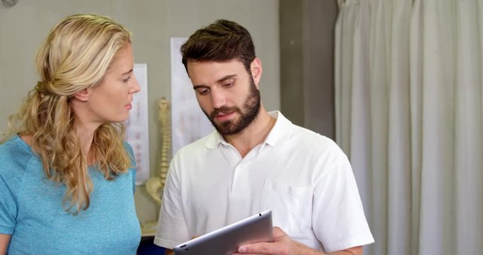 Physiotherapist showing digital tablet to woman in clinic 4k