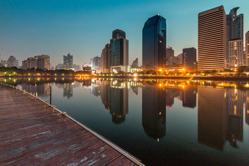 Naklejka premium Bangkok Skyline taken from Benjakiti Park in Bangkok, Thailand, South East Asia in the morning with calm water reflecting buildings themselves.