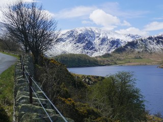 View of snow covered mountains over looking a lake from a roadside 