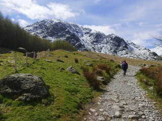 Fototapeta na wymiar Lone walker on footpath to snow covered mountains 