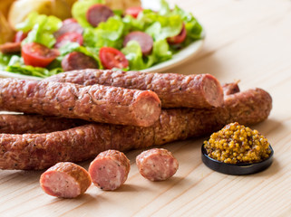 Smoked sausage with vegetables salad on a wooden board