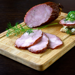 Smoked sausage with herbs on a wooden board