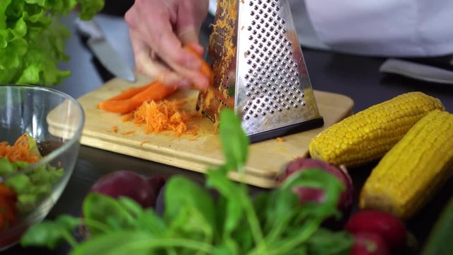 vegetable salad - chef grinding carrot with grater
