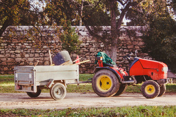 Small garden tractor with trailer and working tools inside in the park