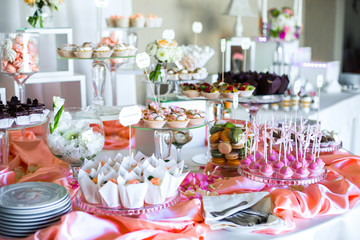 Table with delicious sweets covered with pink silk