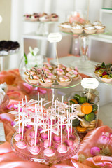 Bowl with green and orange macaroons and plate with pink balls s