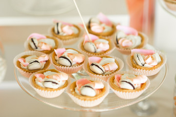 Baked baskets with tiny macaroons served on glass plate