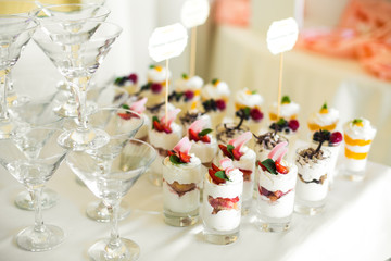 Cold desserts in glass shots stand on white table with beautiful