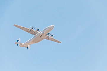 Antonov An-22 Antei (Antaeus, Cock) the world's largest turboprop-powered aircraft flies against blue sky background.
