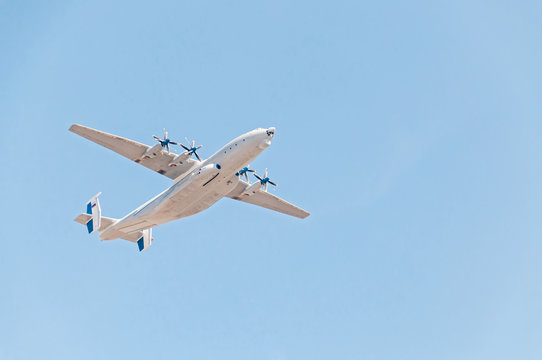 Antonov An-22 Antei (Antaeus, Cock) the world's largest turboprop-powered aircraft flies against blue sky background.

