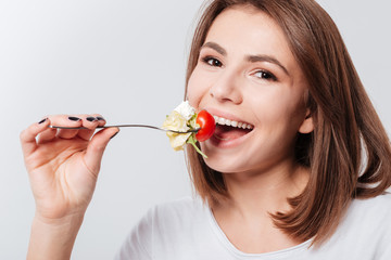 Cheerful young lady eating salad