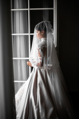 Bride hidden under the veil stands in the entrance to balcony