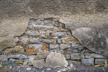 weathered and damaged stone wall with bricks
