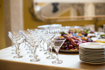 Empty cocktail glasses stand on dinner table with fruits on dish