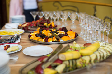 Sliced fruits served on steel dishes stand on table in the resta