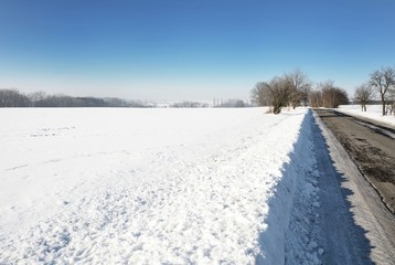 Fototapeta na wymiar Rural winter scene with snowy field and road.