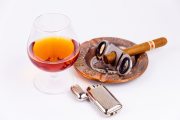 Cognac glass and cigar with ashtray and lighter isolated on white background