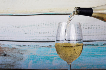 Glass of white wine being poured from bottle