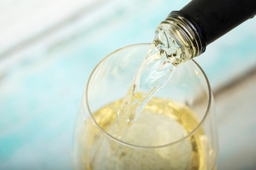 Glass of white wine being poured from bottle